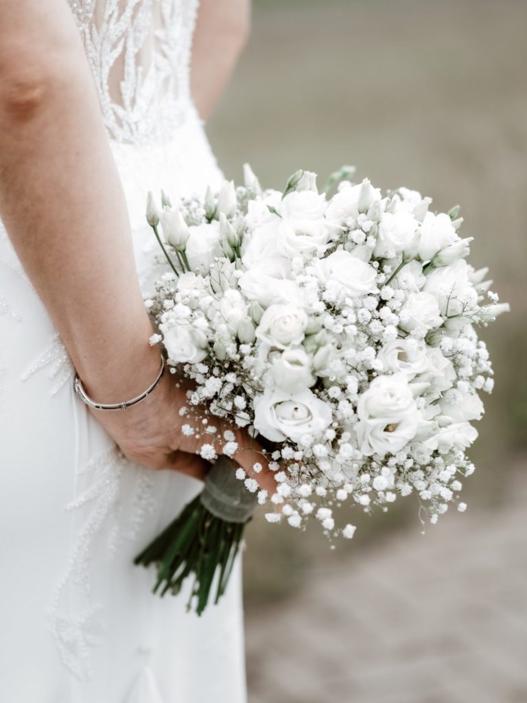 Paar in eleganter Hochzeitskleidung, umarmend am Wasser mit einer romantischen Atmosphäre.