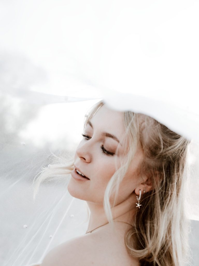 Paar in eleganter Hochzeitskleidung, umarmend am Wasser mit einer romantischen Atmosphäre.